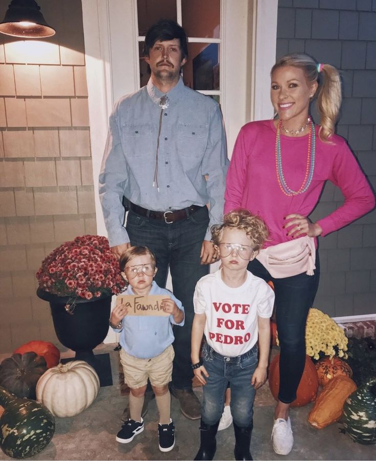 a man, woman and two children standing in front of a house with pumpkins