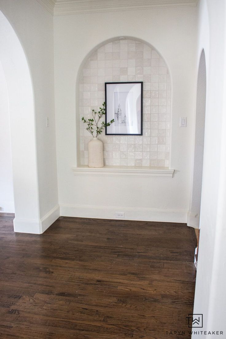 an empty room with white walls and wood flooring is seen in this image from the doorway