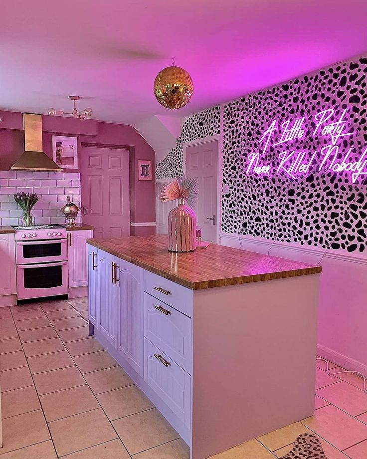 a kitchen with pink walls and white cabinets is lit up by purple lighting above the island