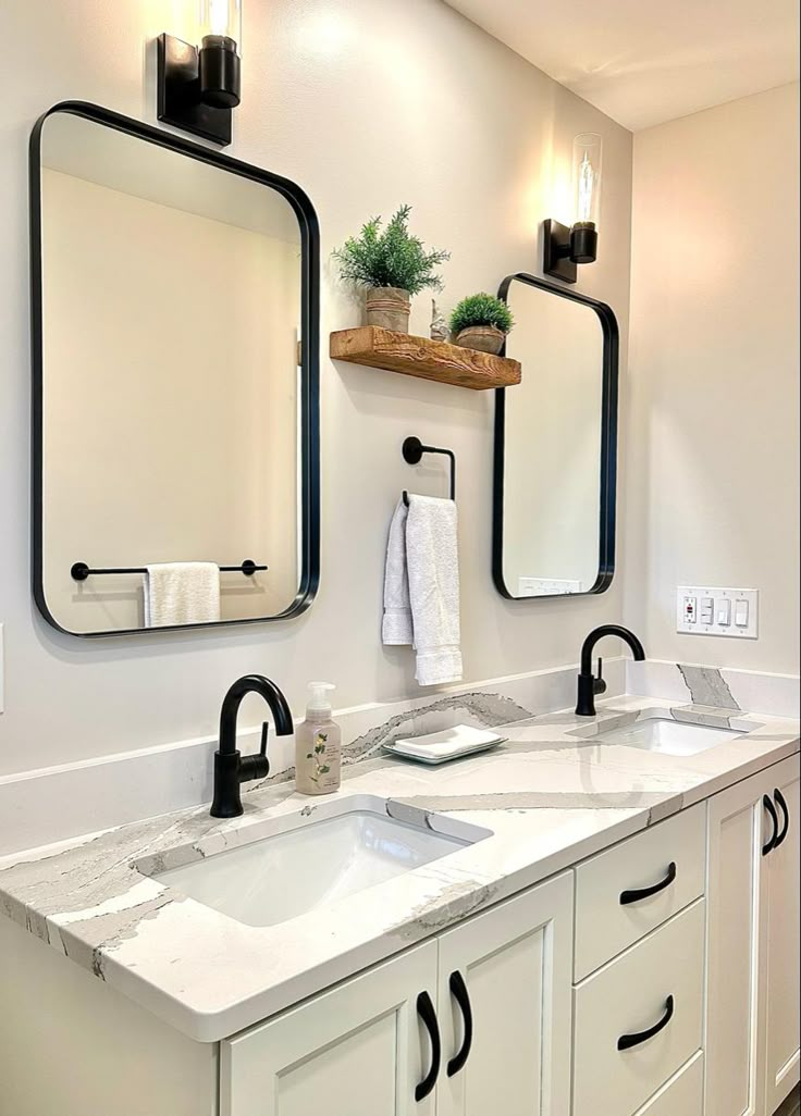 a bathroom with two sinks, mirrors and lights on the wall above them is shown