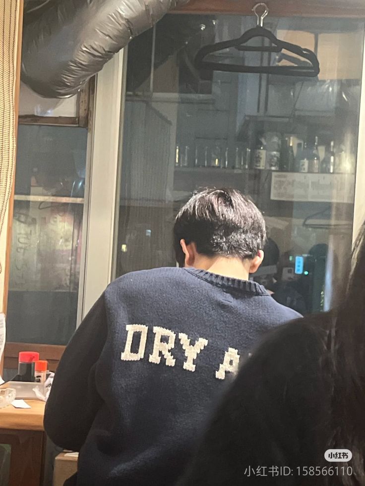 the back of a man wearing a sweatshirt that says dry p in front of a window