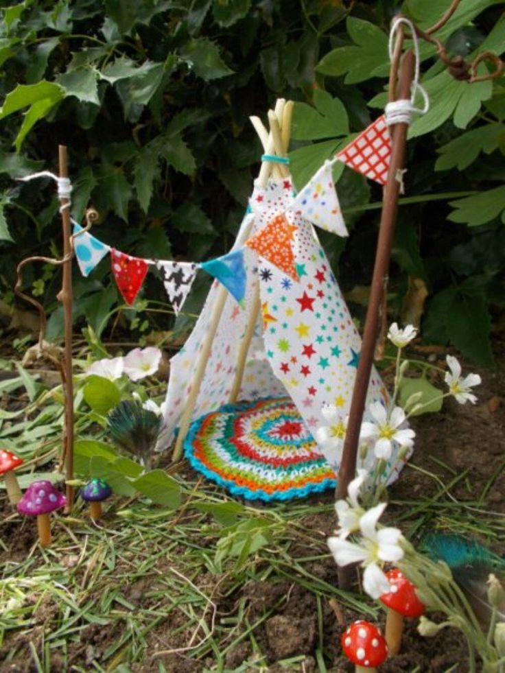 a teepee tent sitting in the grass next to some flowers and mushrooms with flags