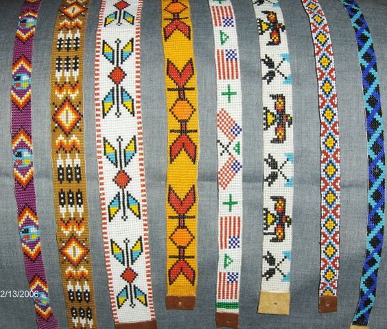 several bracelets are lined up in rows on a gray cloth background, each with different designs and colors