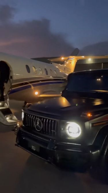 an suv is parked in front of a private jet airplane at night with the lights on