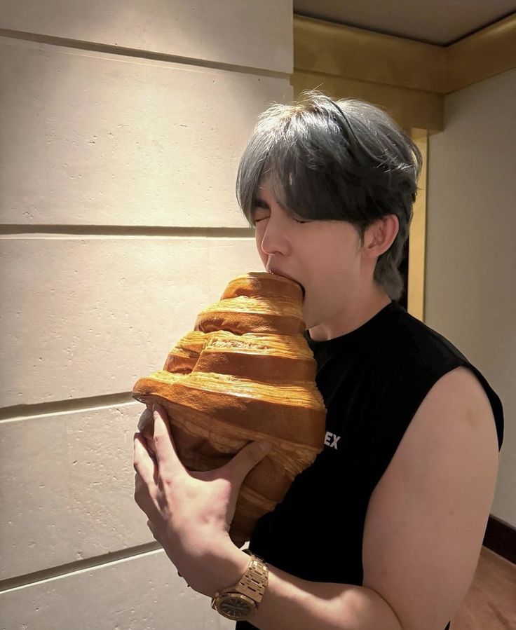 a woman holding a loaf of bread in front of her face while biting into it