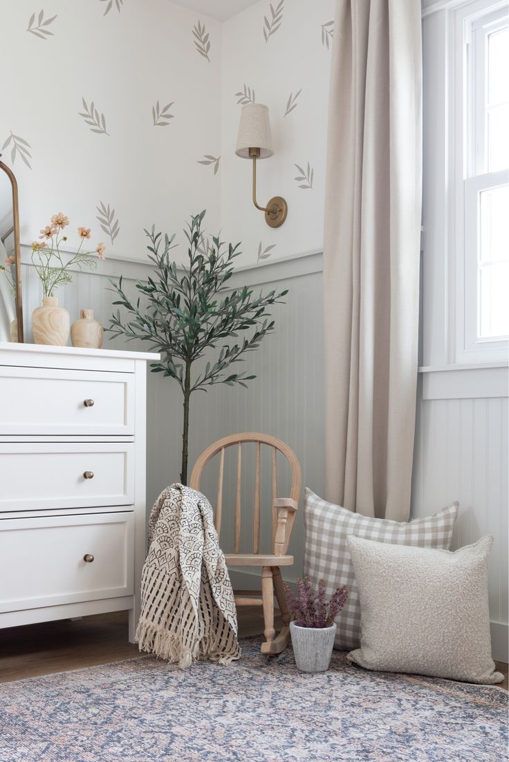 a white dresser and chair in a small room with a rug on the floor next to it