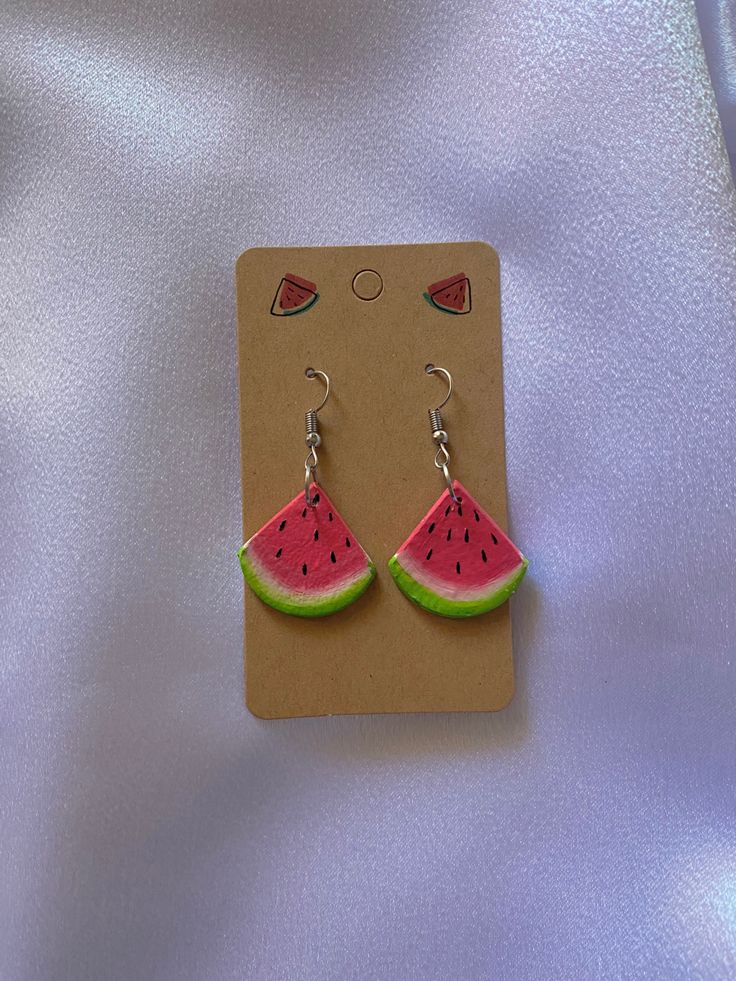 a pair of watermelon shaped earrings sitting on top of a card