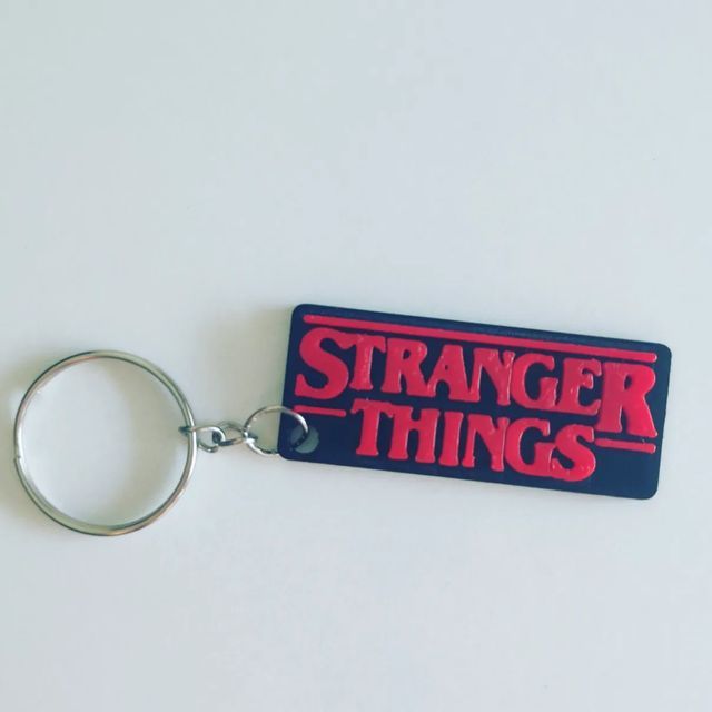 a red and blue keychain with the words strange things printed on it's side