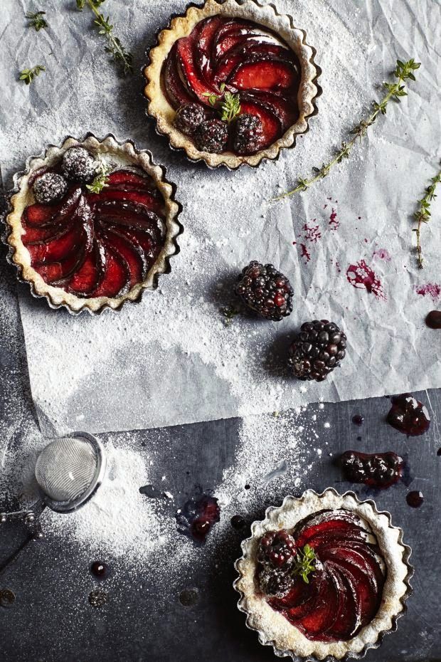 three pies with berries and ice cream sitting on top of a table next to raspberries