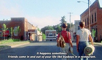 two people walking down the street in front of some buildings with a quote on it