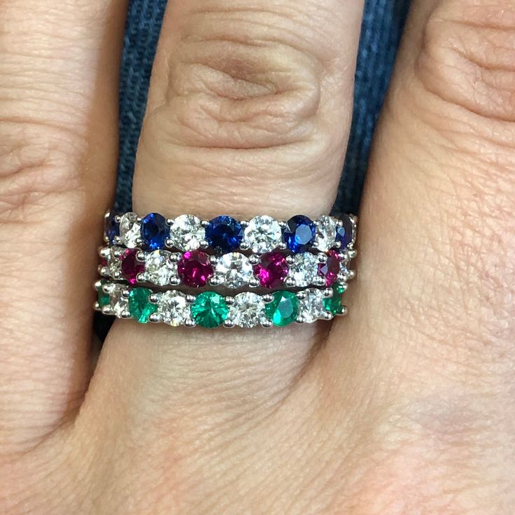 a woman's hand with three different colored stones on it and an engagement ring