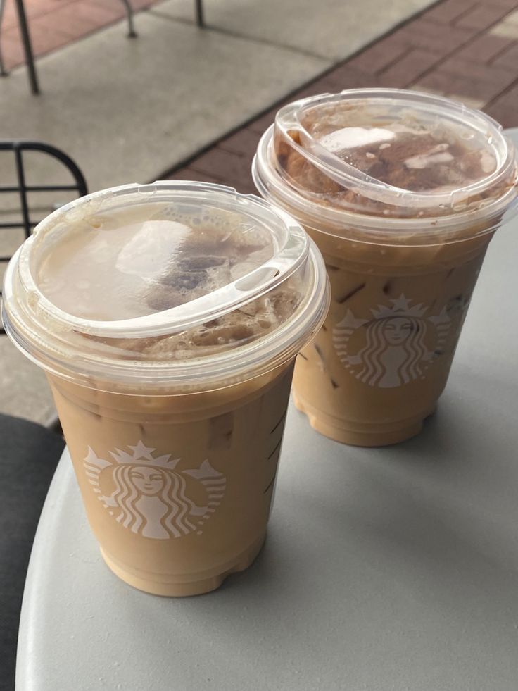 two cups of iced coffee sitting on top of a table