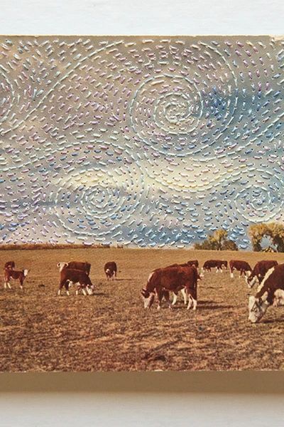 a group of cows grazing in a field under a cloudy blue sky with swirls