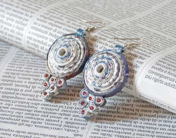 pair of silver and red earrings sitting on top of an open book with pages in the background