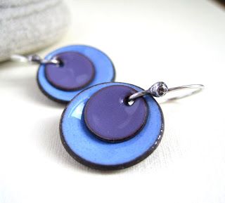 two blue and purple earrings are sitting on a table