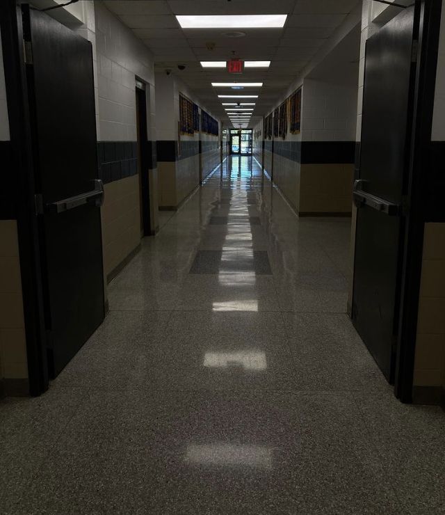 an empty hallway with black doors and white tile on the floor is seen in this image