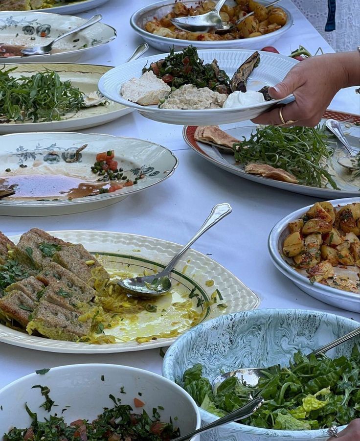 a table topped with lots of plates and bowls filled with different types of food items