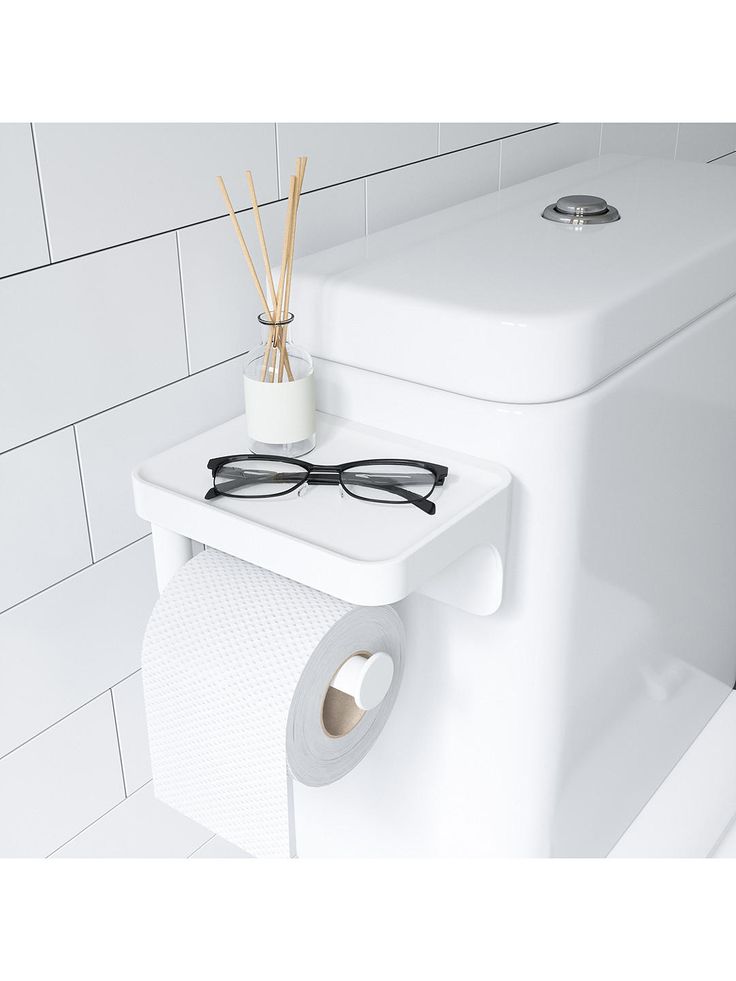 a pair of glasses sitting on top of a toilet paper dispenser next to a roll of toilet paper