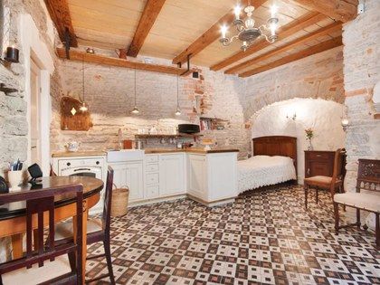 an old fashioned kitchen and dining area in a stone walled building with exposed ceiling beams