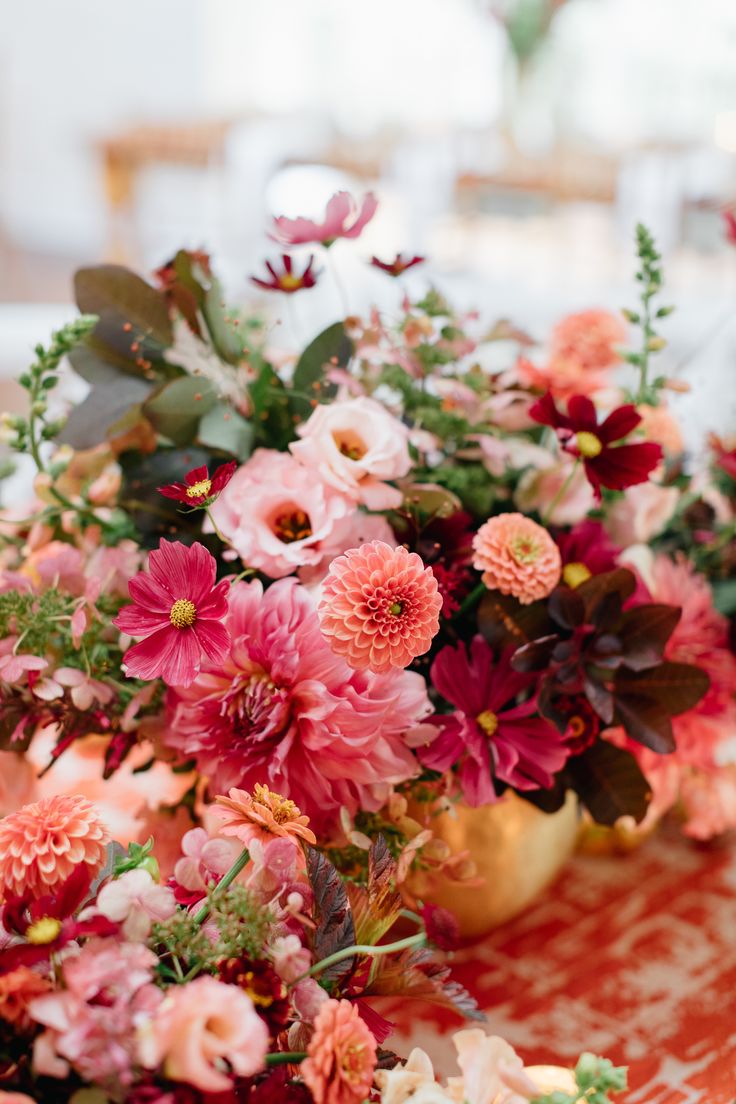 a table topped with vases filled with flowers and greenery on top of it