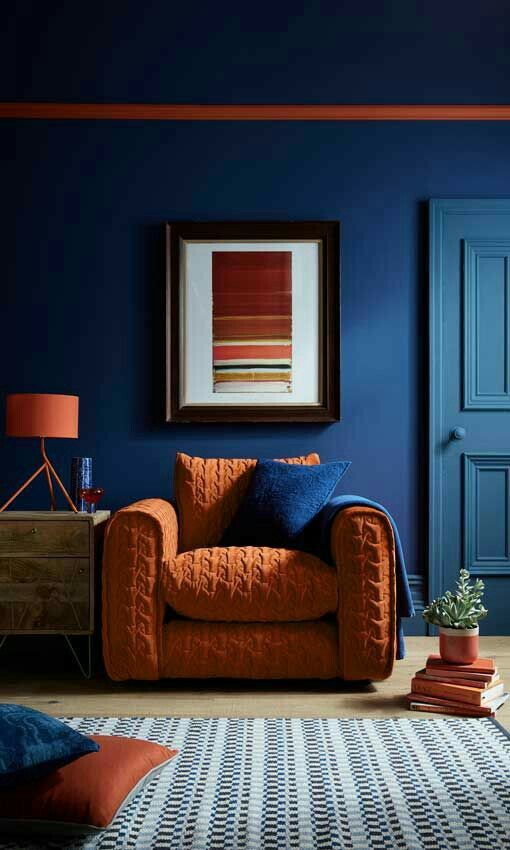 a living room with blue walls and an orange chair