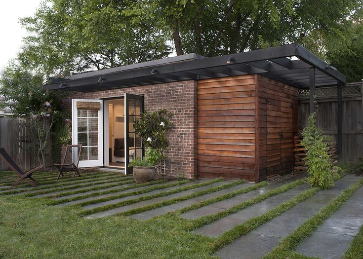 a small brick building sitting on top of a lush green field next to a wooden fence