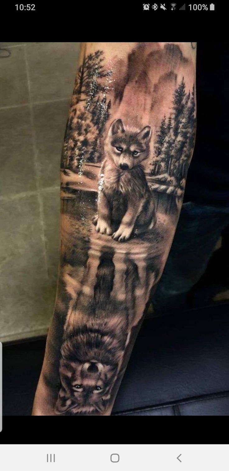 a man with a wolf tattoo on his arm and the reflection of trees in water