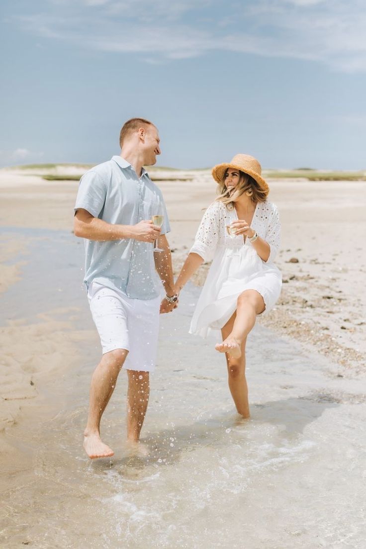 a man and woman are walking in the water at the beach with their feet in the sand