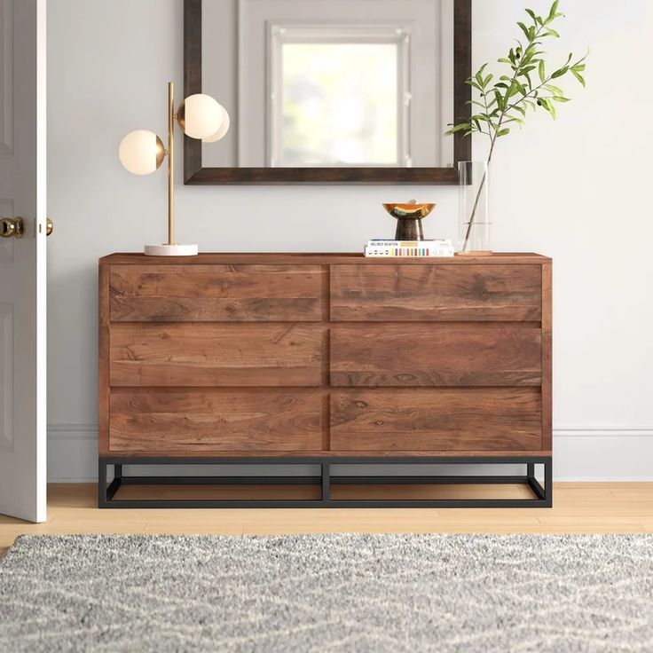 a wooden dresser sitting in front of a mirror on top of a wall next to a door