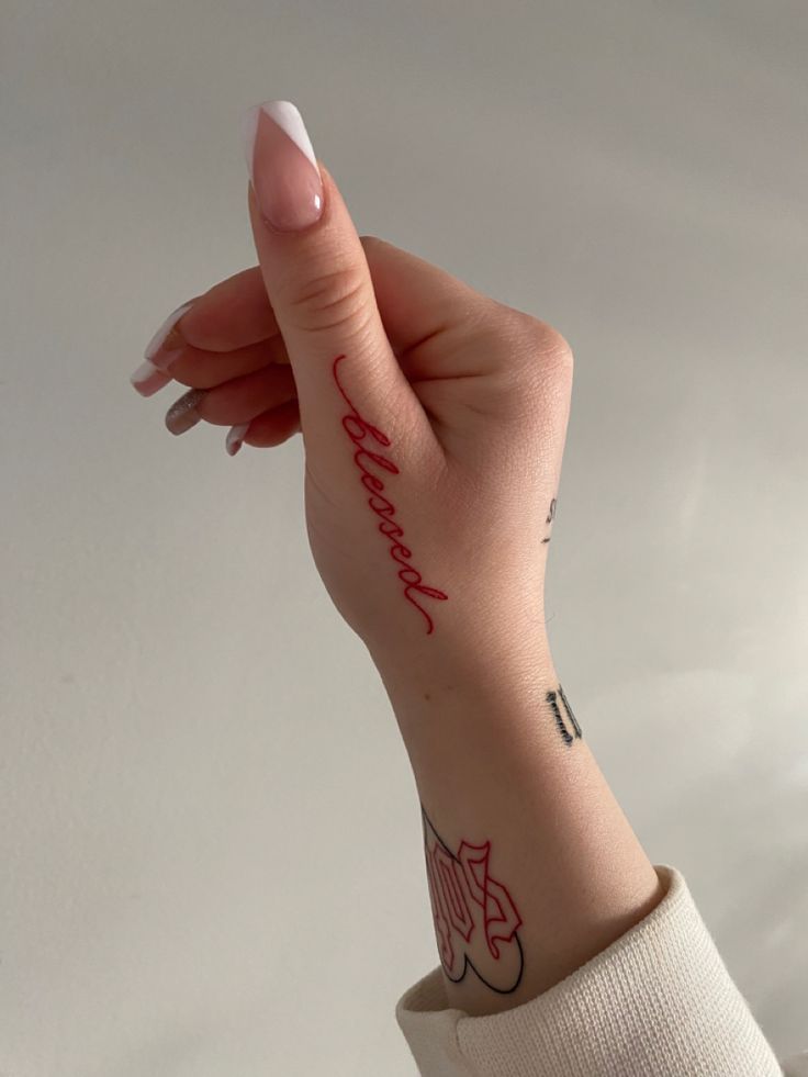 a woman's hand with a tattoo on it and the word love is written in red ink