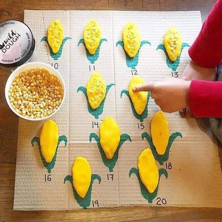 a child pointing at some food on top of a paper towel with corn kernels