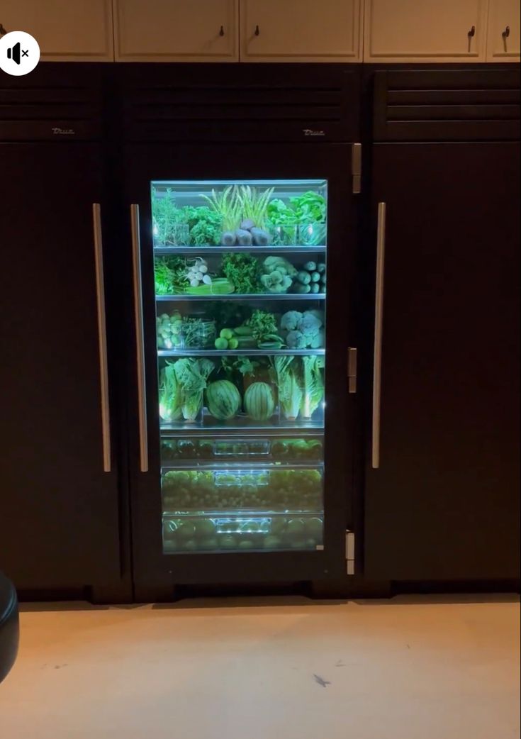 the refrigerator is full of vegetables and other food in it's display case,