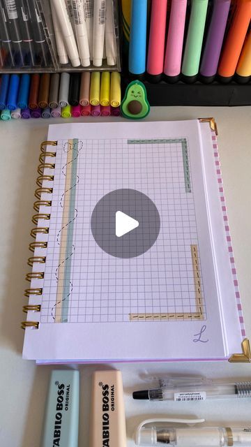 an open notebook sitting on top of a table filled with markers and crayons