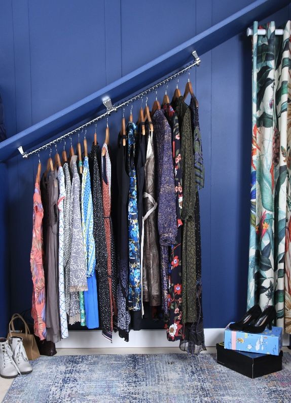 a room with blue walls and lots of clothes hanging on the rack in front of it