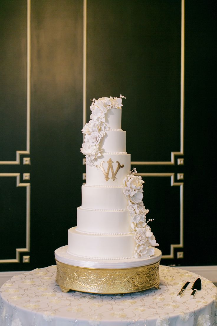 a three tiered white wedding cake with flowers on the top and gold trimmings