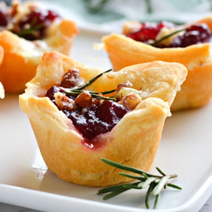 mini cranberry tarts with rosemary garnishes on a white plate