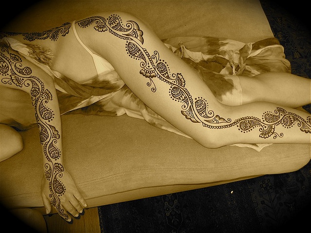 a woman laying on top of a couch covered in hendix tattoo designing