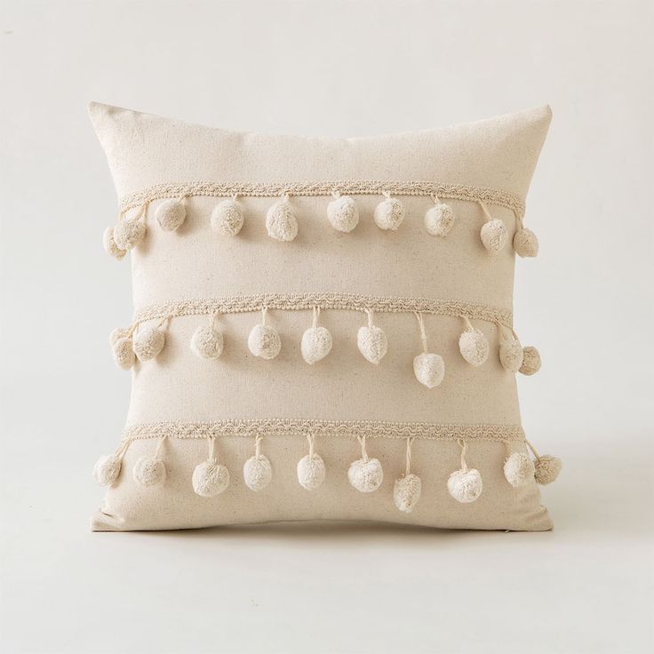 a white pillow with pom - poms on it