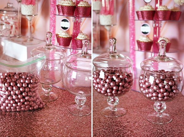 pink and white desserts are displayed in glass containers on a glittery tablecloth