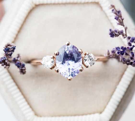 an engagement ring with three stones and lavender flowers