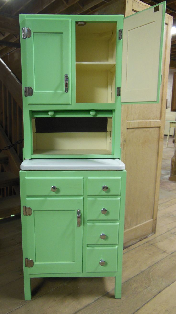 an old fashioned green cabinet with two doors and drawers on the bottom, next to a stair case