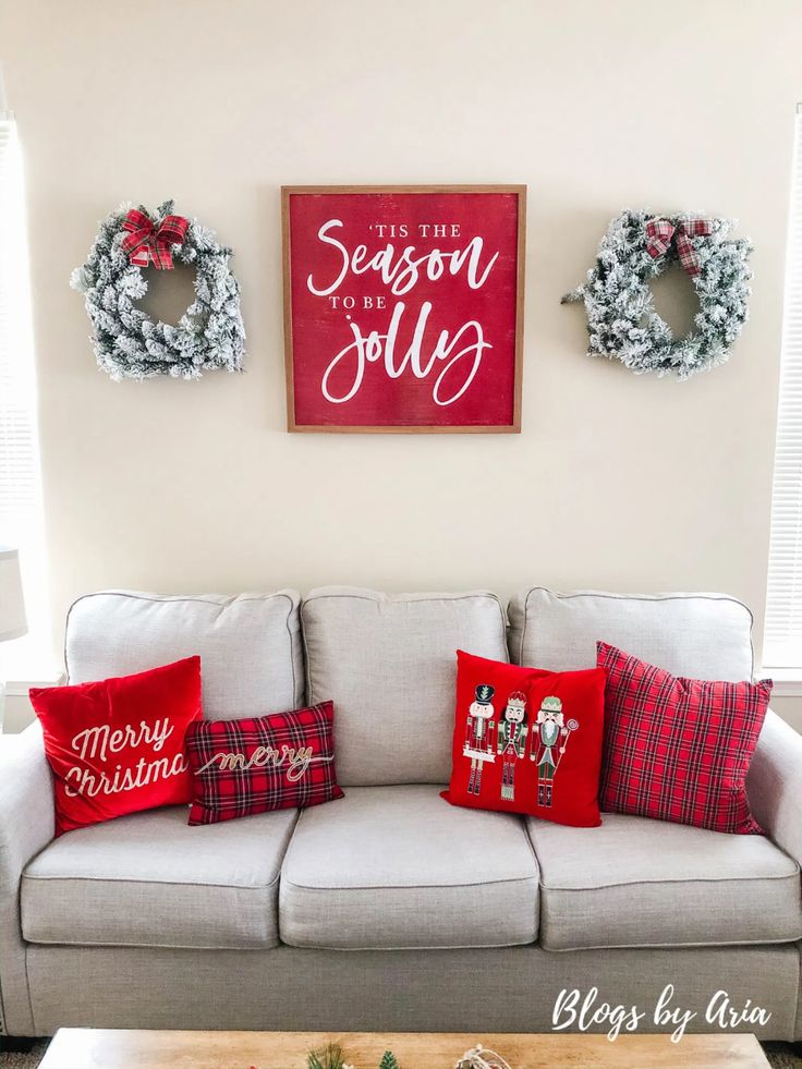 a living room with christmas decorations on the wall and two wreaths above the couch