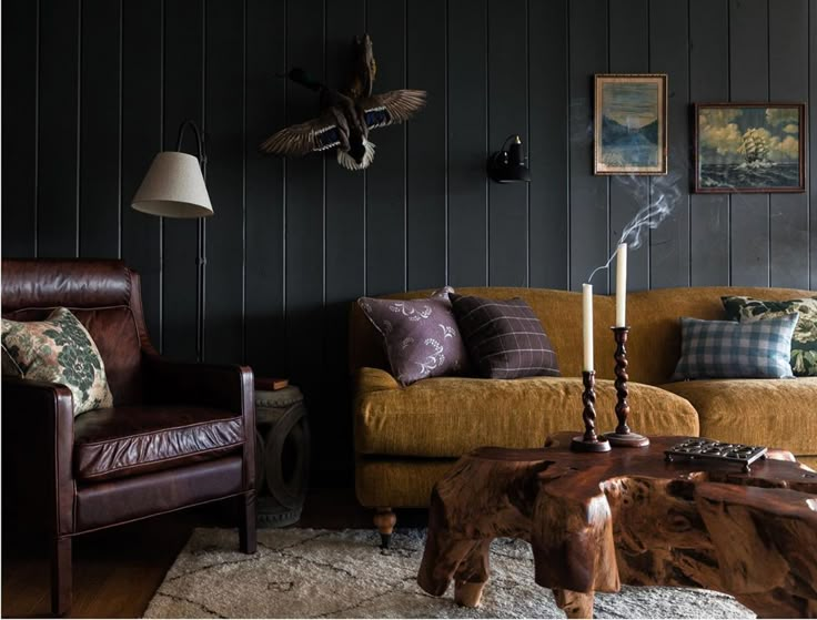 a living room with two couches, a table and pictures on the wall behind them