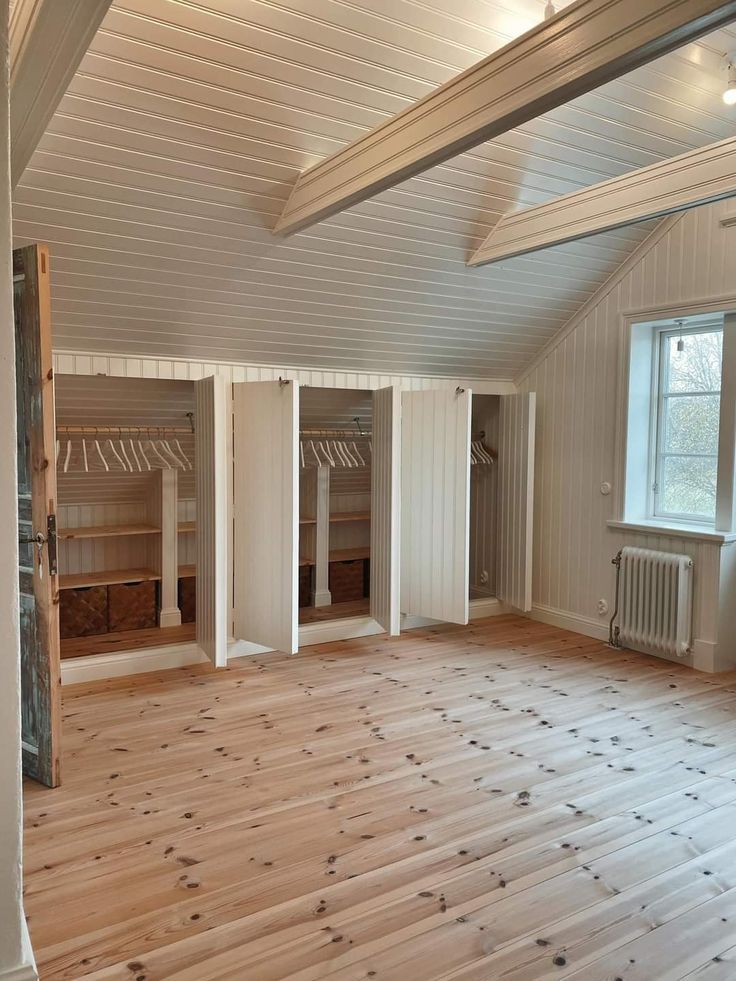 an empty room with wooden floors and white walls