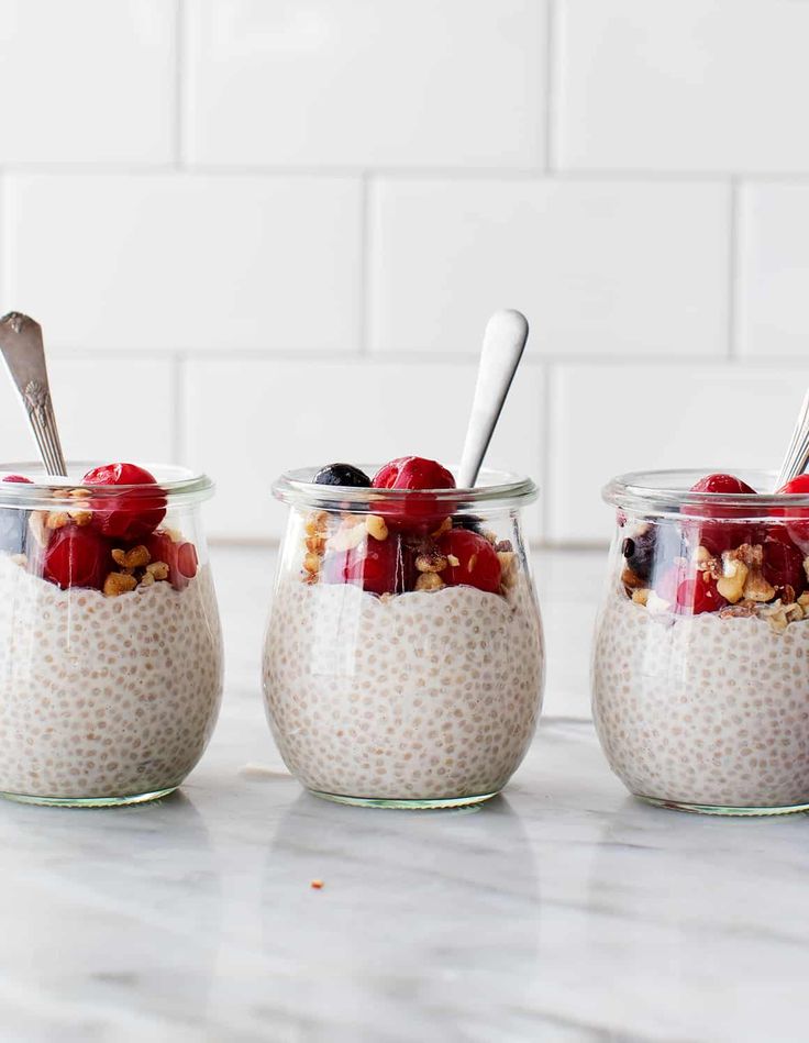 three jars filled with oatmeal and fruit on top of a marble counter