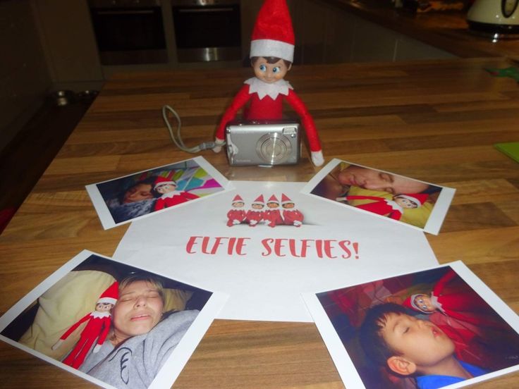 an elf sitting on top of a table next to some pictures and a silver camera