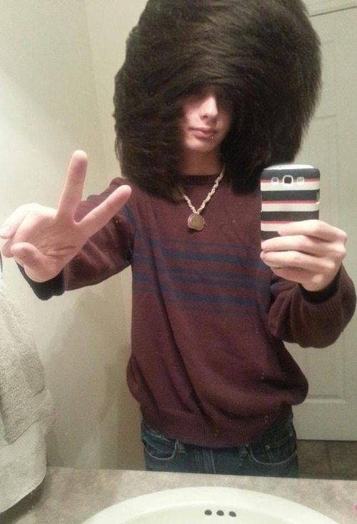 a person taking a selfie in front of a mirror with an afro wig on