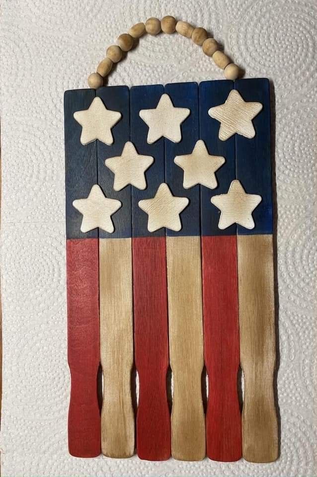 an american flag made out of wood and beads hanging from a string on a wall