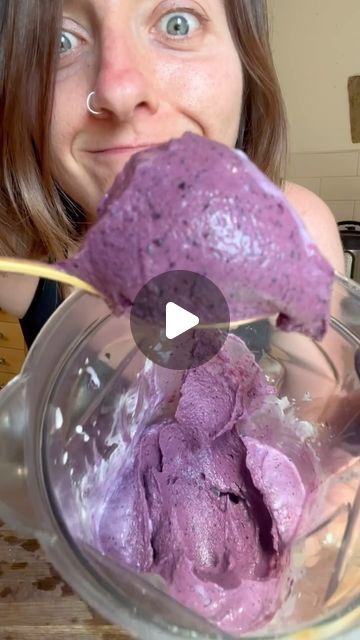 a woman holding a spoon over a bowl filled with purple ice cream