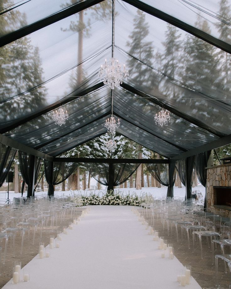 an outdoor wedding venue with clear chairs and chandelier